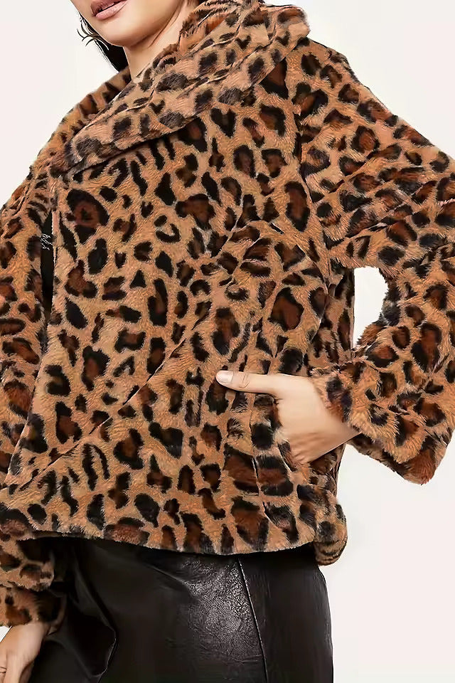 A close-up of a model wearing a brown and black leopard print faux fur jacket with a wide collar and black leather pants against a plain light background.