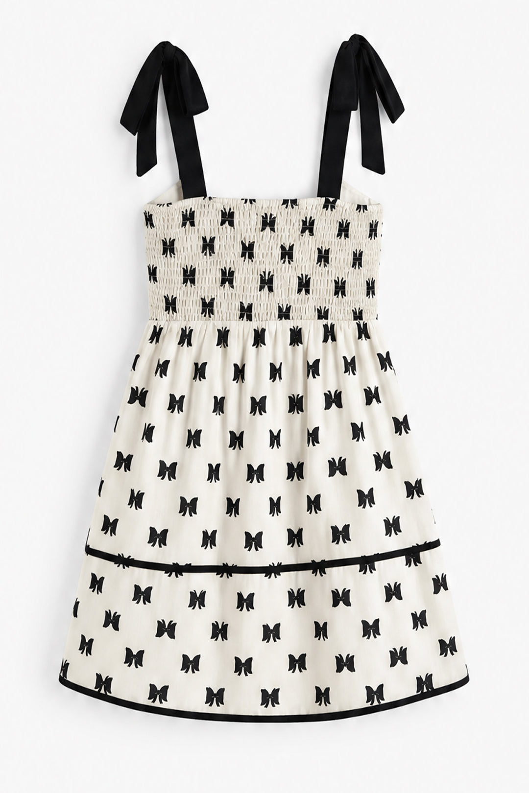 A sleeveless smocked dress with black ribbon shoulder ties, featuring an off-white body with a repeating black bow print and a black horizontal trim line near the hem.