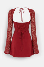 A red mini dress with a lace long-sleeve overlay, a square neckline with tie-back straps, and a lace-up corset-style bodice, shown against a light gray background.