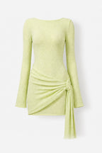 A light lime green long-sleeve knit mini dress with a draped wrap-style skirt and side tie detail, shown against a plain light gray background.