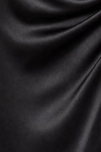 A close-up of draped black satin or silk fabric with soft folds and a subtle sheen.