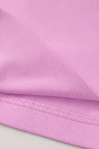 A close-up of light pink fabric with a folded hem showing fine knit texture and stitched edge.