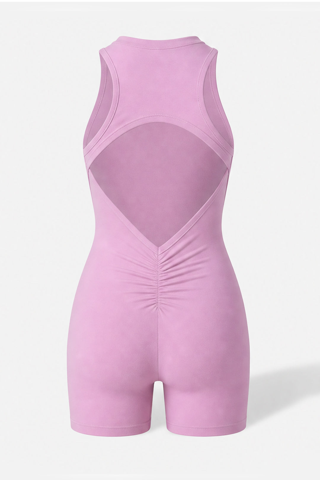 A sleeveless light pink one-piece romper with a large open back design and gathered ruching at the center front, shown on a light gray background.