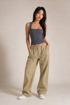 A woman modeling a dark gray ribbed tank top and beige wide-leg cargo pants against a neutral studio backdrop.