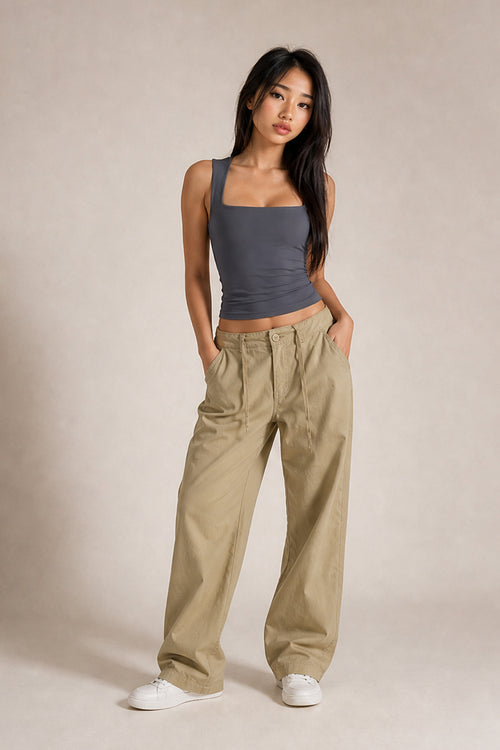 A woman modeling a dark gray ribbed tank top and beige wide-leg cargo pants against a neutral studio backdrop.