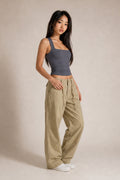 A woman modeling a dark gray ribbed tank top and beige wide-leg cargo pants against a neutral beige studio backdrop.