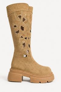 A mid-calf tan suede boot with cutout western-style scrollwork embroidery on the shaft and a chunky lug sole, shown against a plain white background.