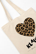 A beige canvas tote bag with a large leopard-print heart graphic on the front and partial black text reading 'KLAUWRA'.