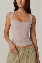 Woman wearing a beige tank top and beige pants against a plain background