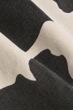 Close-up of a black and off-white cow-print fabric texture with soft folds.