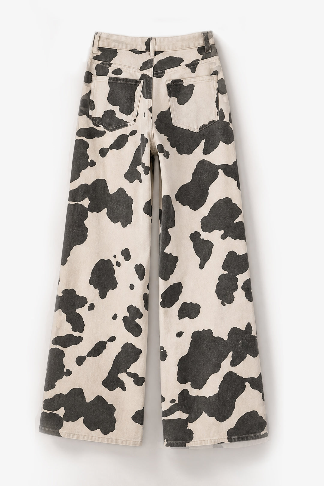 Wide-leg pants featuring a bold black and cream cow print pattern, displayed flat against a clean white background.