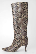 A single knee-high pointed-toe boot with a metallic snakeskin pattern in shades of bronze, brown, and gold, set against a plain light gray background.