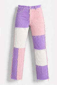 Patchwork denim jeans with a color-blocked design in purple, pink, and off-white, featuring raw frayed edges and a straight-leg silhouette.