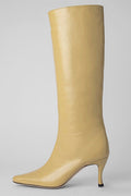 A single knee-high pointed-toe boot in light beige leather with a slim kitten heel, shown against a neutral light gray background.