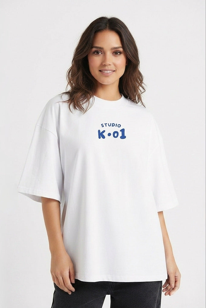 A woman wearing an oversized white t-shirt with a blue graphic print on the chest that reads 'STUDIO K-01'.