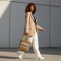 Woman walking outdoors holding a leopard print bag with text.