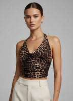 Woman wearing a leopard print halter top and white pants against a gray background